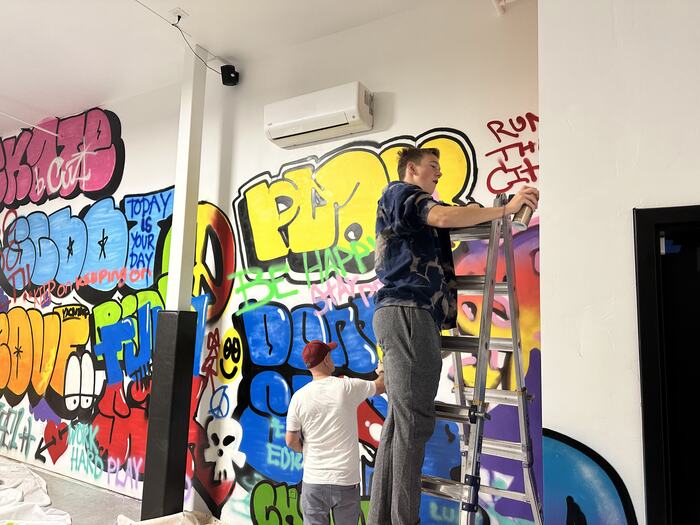 Artists part-way through painting the graffiti wall
