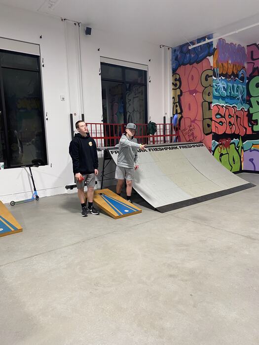 Cornhole in front of the graffiti wall and the ramp