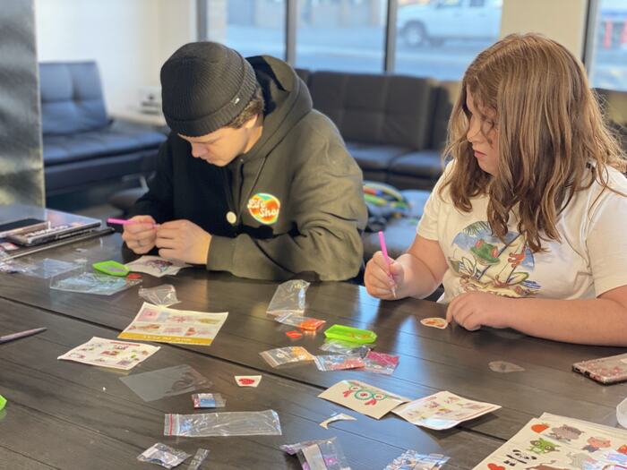 Two teens working on a craft project at the table