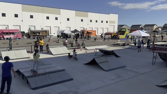 The full mobile skate park set up outdoors with food trucks and tents behind