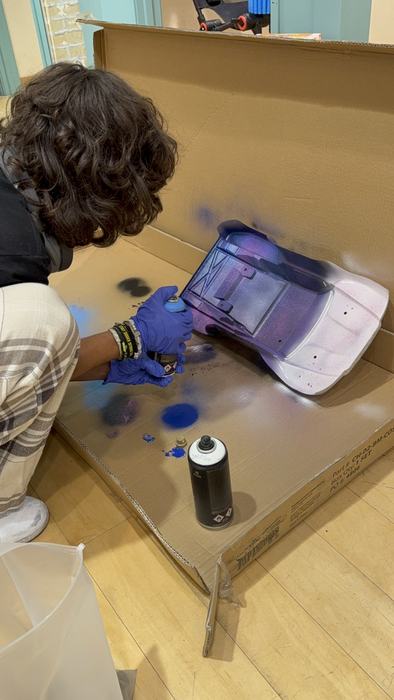 A teen shading an RC body with spray paint