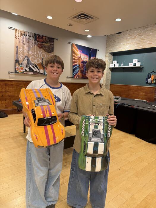 Two teens holding the RC car bodies they painted and built in Auto Shop